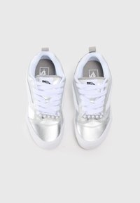 Adidași argintii cu un finisaj lucios, șireturi albe și un accent de perlă pe zona șireturilor. Prezintă un guler căptușit și un logo pe limba adidașului.