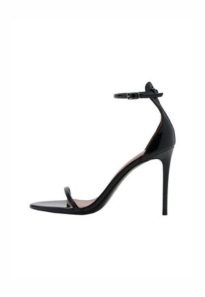 Sandalia de tacón stiletto en charol negro con tira fina en el tobillo y hebilla, una única tira frontal y tacón fino y puntiagudo.