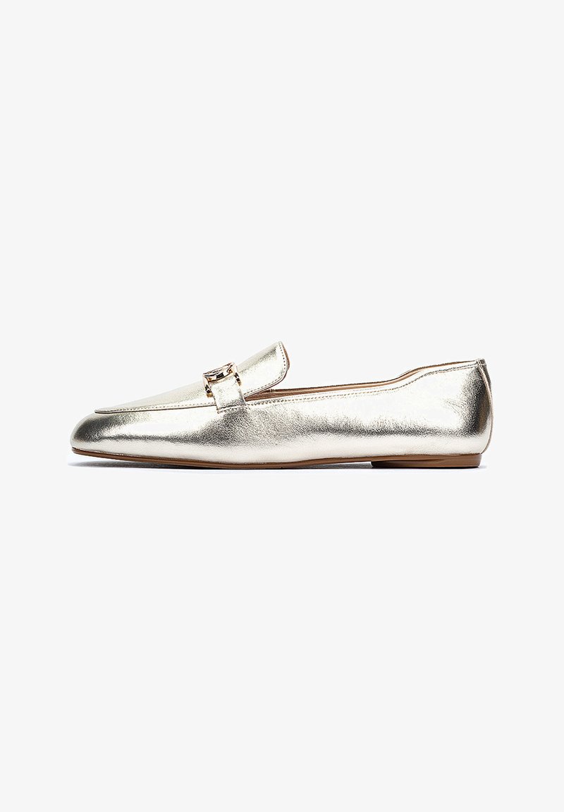 Mocassins dorés métalliques avec un design élégant et plat. Comprend une petite sangle et un détail de boucle sur le dessus. Texture lisse avec un embout arrondi.