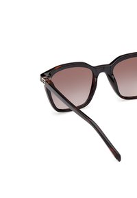 Gafas de sol carey con un marco geométrico y lentes degradados. Entre sus características se incluyen un marco grueso y brazos elegantes y taperados para un diseño moderno.