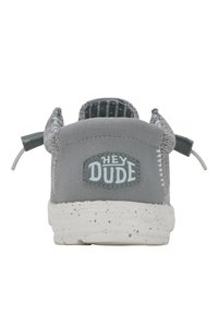 Graue Schlupfschuhe mit einem strukturierten Obermaterial, das ein "HEY DUDE"-Logo-Patch, elastische Schnürsenkel und eine gesprenkelte weiße Sohle aufweist.