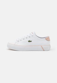 White low-top sneaker with pink accents, white laces, textured sole, and green crocodile logo on side, viewed from the outer side.