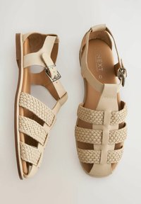 Beige sandals with a woven strap design, featuring smooth leather material, an ankle strap with a buckle, and open-toe structure.