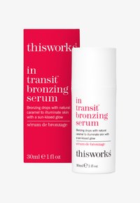 Bottiglia cilindrica bianca con pompa, etichettata "thisworks in transit bronzing serum". Scatola rossa con testo bianco. Dimensione indicata di 30 ml.