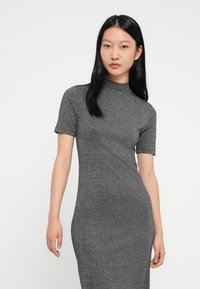 Šedé žebrované šaty s vysokým výstřihem a krátkými rukávy, s přiléhavým střihem, který sahá do poloviny lýtek. Hladká textura po celém povrchu.