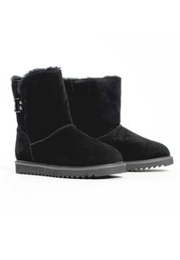 Botas de tobillo de ante negro con un suave forro de piel, que cuentan con una suela de goma texturizada y detalles en hardware plateado en el lateral.