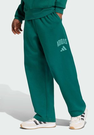 Green cotton blend sweatpants with elastic waistband, featuring "ADIDAS" logo in light green, paired with light-colored sneakers.