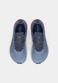 Trail running shoes with a mesh upper in light blue, dark blue laces, and pink accents. Rounded sole with textured tread for grip.