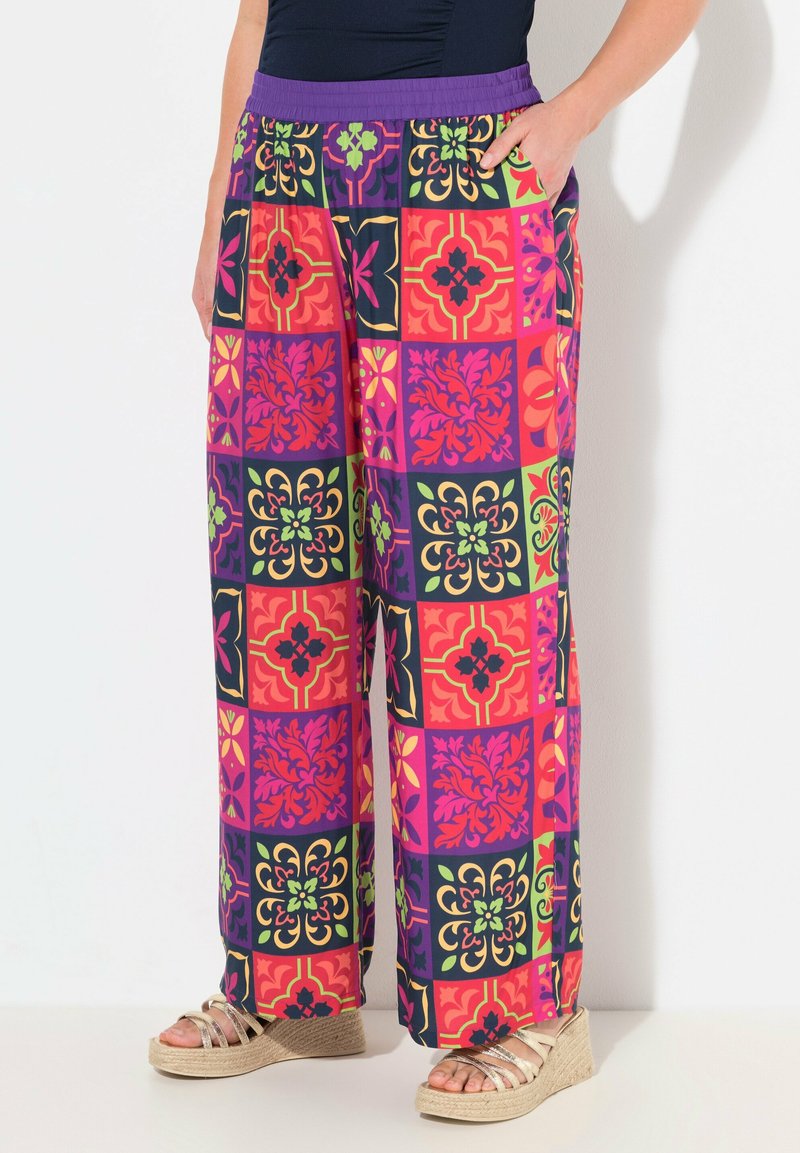 Kleurige wijde broek met een patchworkontwerp, voorzien van bloemen- en geometrische patronen in tinten van roze, paars, groen en zwart.