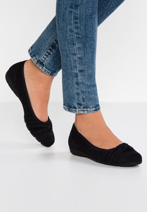 Mustat mokkanahkakengät, joissa on solmittu yksityiskohta varpaassa, matala korko ja teksturoitu pinta; yhdistettyjä sinisiin farkkuihin.