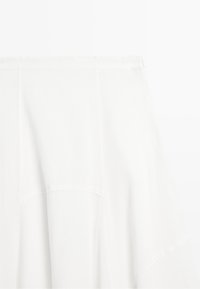 White skirt with a flowy, layered design and a fitted waistband shown on a plain background.