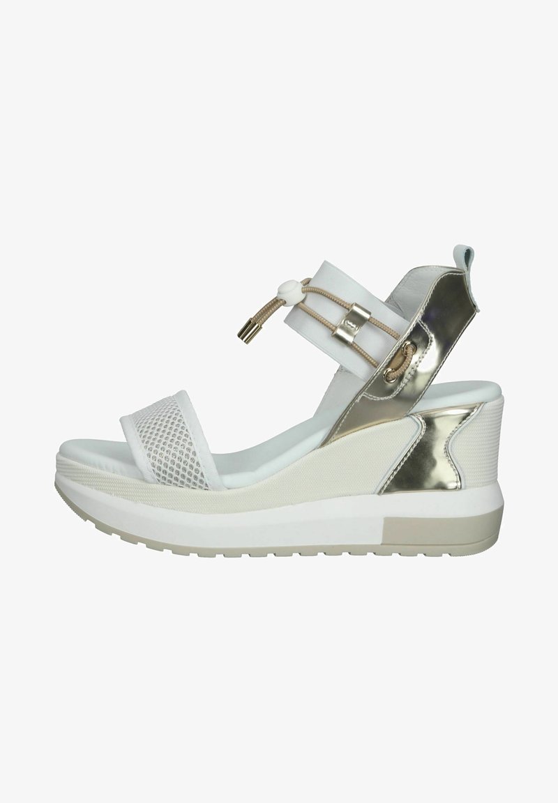 Sandale en wedge blanche avec une bride de orteil en maille, des accents métalliques, une bride élastique à la cheville et une semelle plateforme texturée.