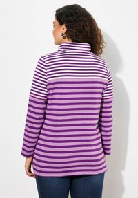 Camisetta a maniche lunghe a righe viola e lavanda con colletto a risvolto, caratterizzata da un'orlo curvo e un morbido materiale in cotone.