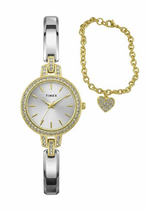 Montre Timex en or et argent avec accents en cristal et bracelet chaîne en or orné d'un charm en forme de cœur incrusté de cristaux.