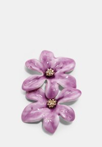 Fialová keramická kvetinová brošňa so zlatými detailmi v strede, s tvarmi pripomínajúcimi okvetné lístky a lesklým povrchom.