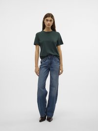 Grønn bomull t-skjorte med korte ermer, kombinert med vide, blå denim jeans. Brune spisse støvler kompletterer antrekket.