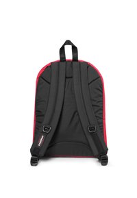 Mochila negra con un ribete rojo, que cuenta con correas acolchadas y ajustables, respaldo plano y un pequeño logo cerca de la parte inferior de una de las correas.