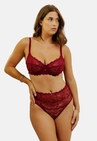 Ensemble de soutien-gorge en dentelle bordeaux et culotte taille haute avec des motifs floraux, des bords festonnés et des fines bretelles. Texture douce avec un accent en V visible.