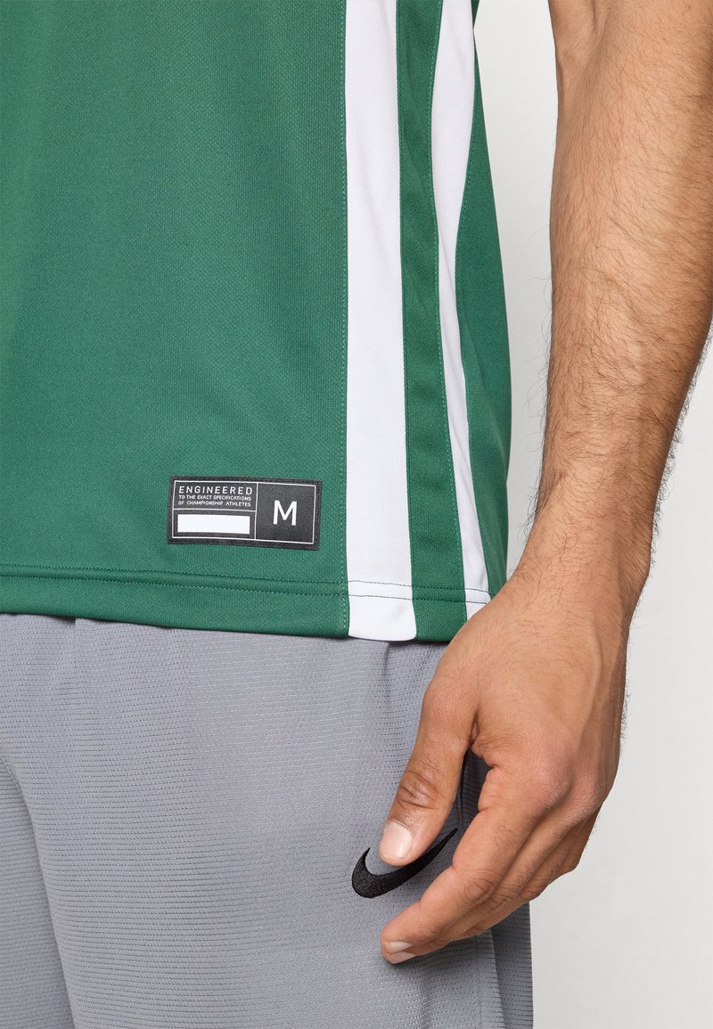 Groene sportshirt met witte zijstreep, gemaakt van ademend materiaal. Beschikt over een label met maat "M" en merkdetails. Grijze short inbegrepen.