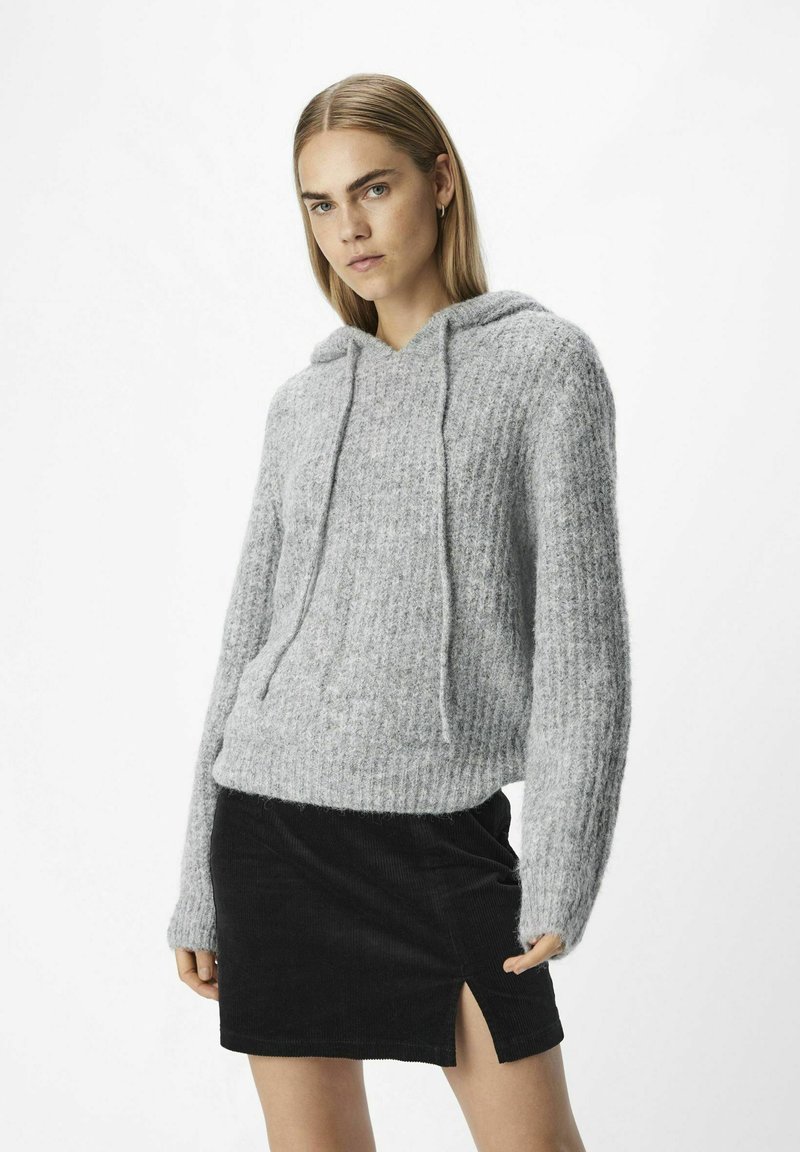 Grå, ribbad stickad hoodie med dragskor, featuring långa ärmar och en avslappnad passform. Matchad med en svart kordflorse mini kjol med en slits.