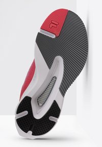 Sohle eines Sneakers mit schwarzem Gummigrip, roten und grauen Akzenten, strukturierten Mustern und einem sichtbaren Luftpolsterbereich.