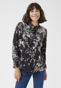 Langarmige zwarte blouse met een bloemendessin in grijs en wit. Voorzien van een knoopsluiting aan de voorkant en elastische manchetten; gladde stoftextuur.