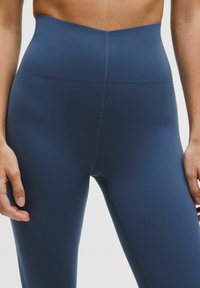 Högmidjade leggings i en solid navy stretchtyg. Har en slät textur, sömlös design och en åtsittande silhuett.