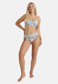 Bikini set s kvetinovým vzorom v modro-ružovej farebnej schéme. Vrchná časť má tenké ramienka; spodná časť má vysoký strih s dekoratívnymi akcentmi.