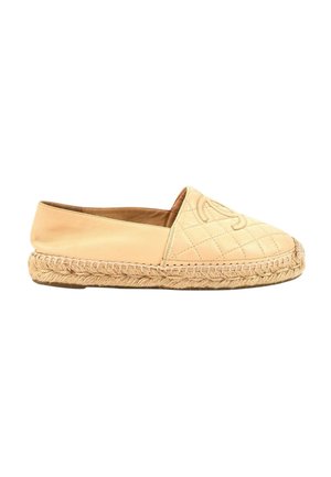 Espadrille en cuir beige avec coutures matelassées, semelle en corde tressée, et logo embossé sur la partie avant supérieure.