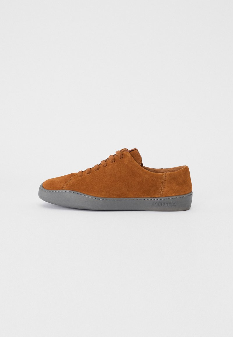 Zapatillas de ante marrón con un perfil bajo, suela de goma gris y punta redondeada, que presentan un diseño de cordones simple. Los acentos incluyen costuras sutiles.