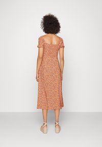 Robe midi florale orange et crème, avec des manches courtes bouffantes, un dos carré et une taille cintrée qui s'évasent à l'ourlet.