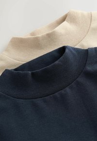 Zwei Rollkragenpullover, einer beige und einer navy, präsentiert mit Nahaufnahme der gerippten Kragen und der weichen, glatten Stoffstruktur.