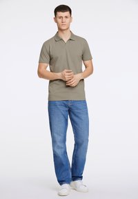 Khaki polo shirt med korte ærmer, parret med blå lige bukser og hvide sneakers. Simpelt, klassisk design med et minimalistisk udseende.