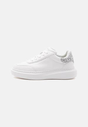 Λευκό χαμηλό sneaker με χοντρή σόλα και ασημένια γκλίτερ λεπτομέρεια στη φτέρνα, πλαϊνή ανάγλυφη με το όνομα της μάρκας.