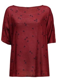 Blouse rouge ample à manches courtes avec de petits motifs floraux foncés dispersés sur le tissu et un large col rond.