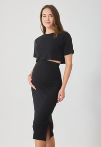 Μαύρο ριγέ σετ δύο τεμαχίων που περιλαμβάνει ένα κοντό τοπ και μια εφαρμοστή φούστα με πλαϊνό άνοιγμα. Το υλικό διαθέτει λεία υφή και ελαστική εφαρ�μογή.