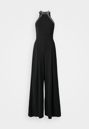 Combinaison noire avec un design à encolure halter, ornée de bords embellis. Silhouette à jambes larges avec des détails plissés à l'avant.