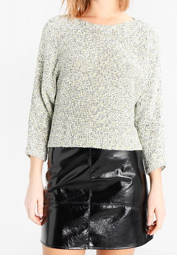 Maglione verde chiaro testurizzato con maniche a tre quarti abbinato a una mini gonna nera in ecopelle con dettaglio della cucitura frontale.