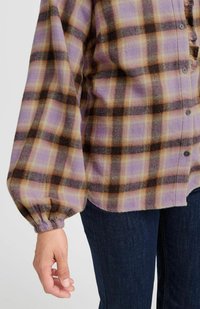 Chemise à carreaux prune et marron avec des manches longues et amples, et une finition texturée. Comprend cinq boutons et un ourlet effiloché.