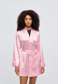 Ροζ σατέν ρόμπα με μακριά μανίκια, ζώνη στη μέση και διακριτικό σχέδιο με καρδιές. Διαθέτει γιακά σάλι και λεία υφή.