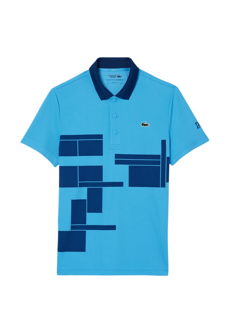 Chemise polo bleue avec des motifs géométriques navy, un col navy uni et trois boutons. Présente un petit logo crocodile vert sur la poitrine.