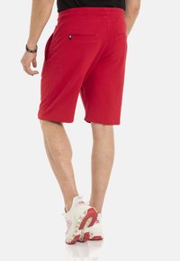 Rode shorts van een katoenmix met een elastische tailleband; voorzien van twee zijzakken en één achterzak; gladde textuur, knielengte.
