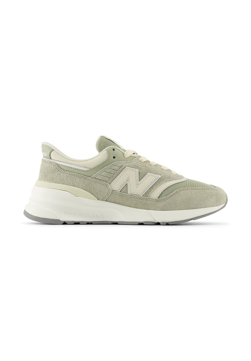 Sneaker New Balance verde chiaro e beige con pannelli in suede e mesh, suola bianca spessa e design con lacci, mostrata da una vista laterale.