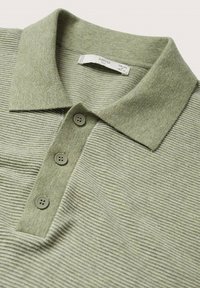 Polo à rayures vertes avec col, doté de trois boutons, texture côtelée, et une étiquette intérieure indiquant la marque et la taille.