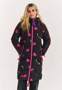 Černá péřová bunda s barevnými vyšívanými srdíčky a vzory, kontrastním růžovým zipem a stahovacími prvky na límci a manžetách.