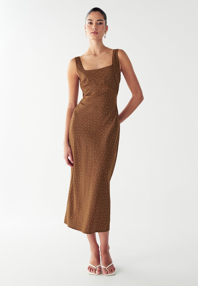 Vestido midi marrón con escote cuadrado, cuerpo ajustado y un sutil patrón de lunares. Tejido suave con un ligero brillo, diseño sin mangas.