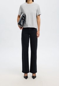 Graues Baumwoll-T-Shirt, lockere Passform. Schwarze High-Waist-Jeans, weit geschnitten. Schwarze spitze Pumps. Schwarze Lederhandtasche mit Bindedetail.