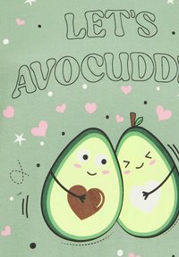 Grön T-shirt med två tecknade avokado som kramas, med en ljusgrön bakgrund, texten "Låt oss avokuddle", rosa hjärtan och svarta prickar.