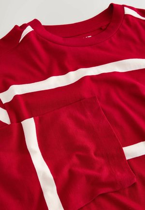 Camiseta de algodón roja con rayas horizontales blancas; presenta un cuello redondo y un bolsillo aplicado en el lado izquierdo. Textura suave.