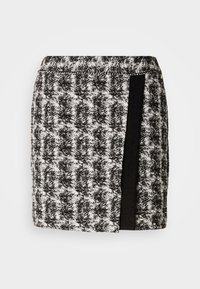 Juoda ir balta houndstooth sijonas su elastinga juosta, turintis juodos medžiagos panelę šone. Trumpas ilgis, tekstūruota medžiaga.
